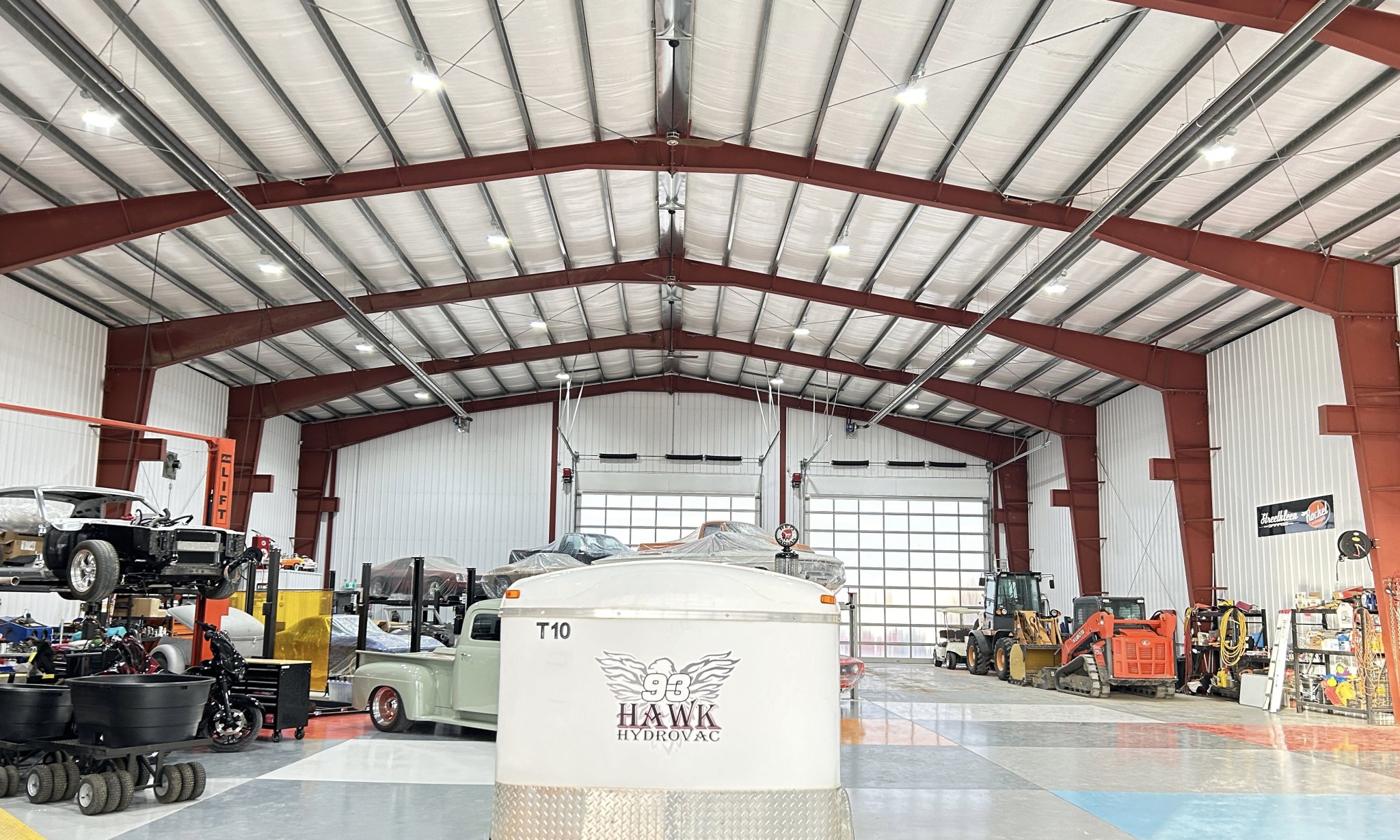 Overhead Reflect-O-Ray radiant tube heater installed in an industrial warehouse shop, mounted to the ceiling above the maintenance work area