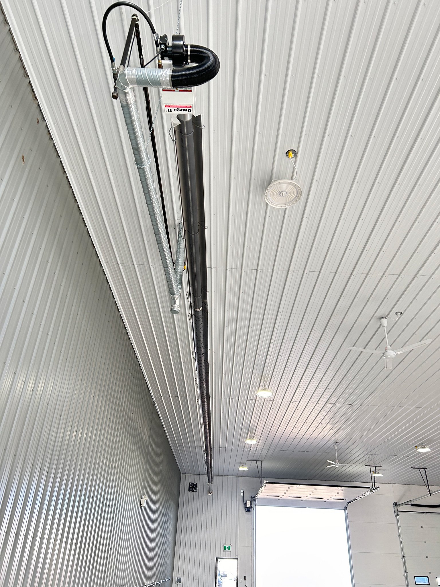 Radiant tube heater installed overhead in a working shop, mounted along the ceiling above the work floor