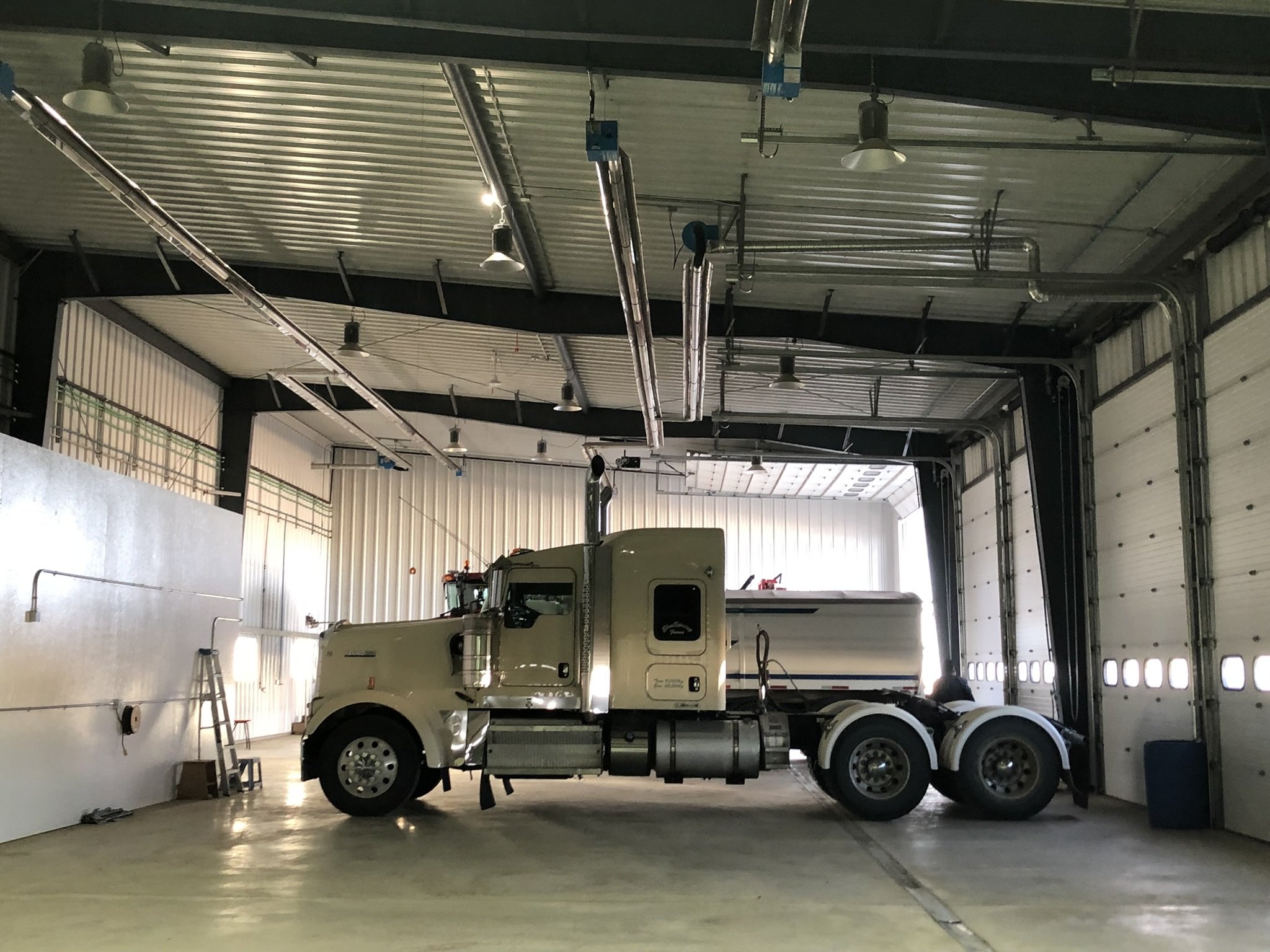 Overhead radiant tube heater in a vehicle service shop, ceiling-mounted along the work bay